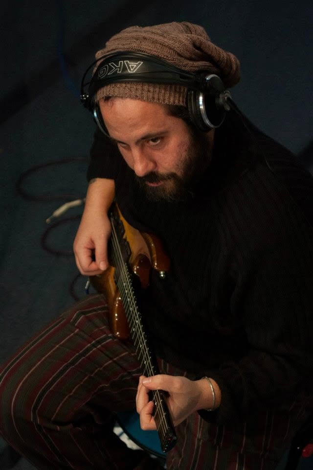 Alessandro in studio con chitarra e cuffie
